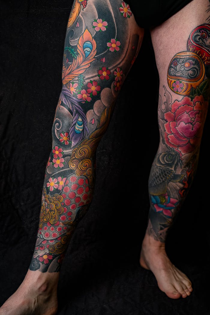 Colorful tattoos on legs with intricate artistic designs and floral patterns.