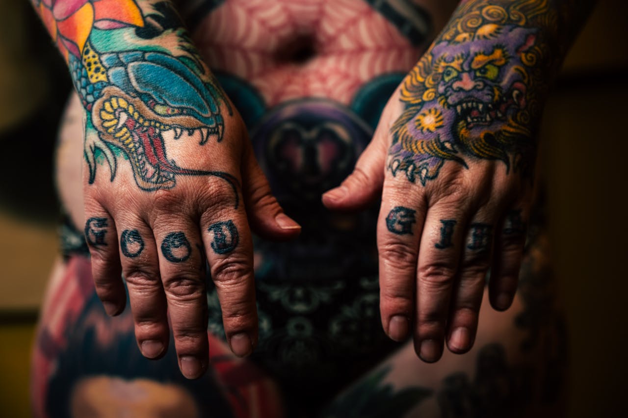 Close-up of vibrant tattooed hands with detailed dragon and mythical designs.